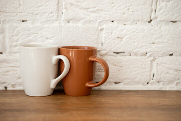 brown and white cups stand on a wooden table near a white wall