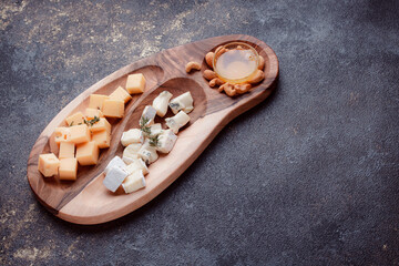 Cheese cut into pieces on a wooden board. Serving cheeses with honey and nuts. The concept of a...