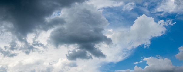 Dark storm clouds cover the blue sky with white clouds
