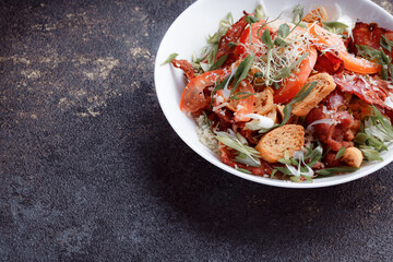 Salad panzanella of tomatoes and paper with fresh greens. Fresh vegetable mix at dark table. Top view, Copy space.