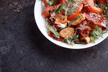 Salad panzanella of tomatoes and paper with fresh greens. Fresh vegetable mix at dark table. Top view, Copy space.