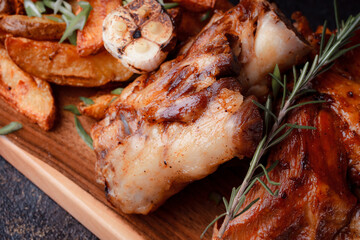 A set dish: a large fried piece of meat on the bone, country-style grilled potatoes, a mini salad of cabbage, bean sprouts, chia seeds and green onions. Original serving on a wooden cutting board.