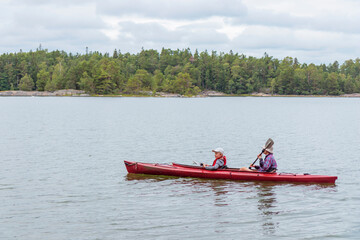 Father and son together, family activity by kayaking in the archipelago, canoeing, boating in the Baltic sea during summer vacations in Finland