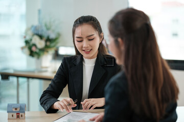 Two women are sitting at a table, one of them is writing on a piece of paper