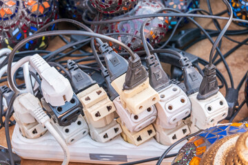 Old and damaged electric adapter power plug has many appliances are plugged outlet socket concept...