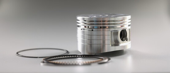 Silver mechanical round part of the engine piston on a gray background, close-up. New shiny auto...