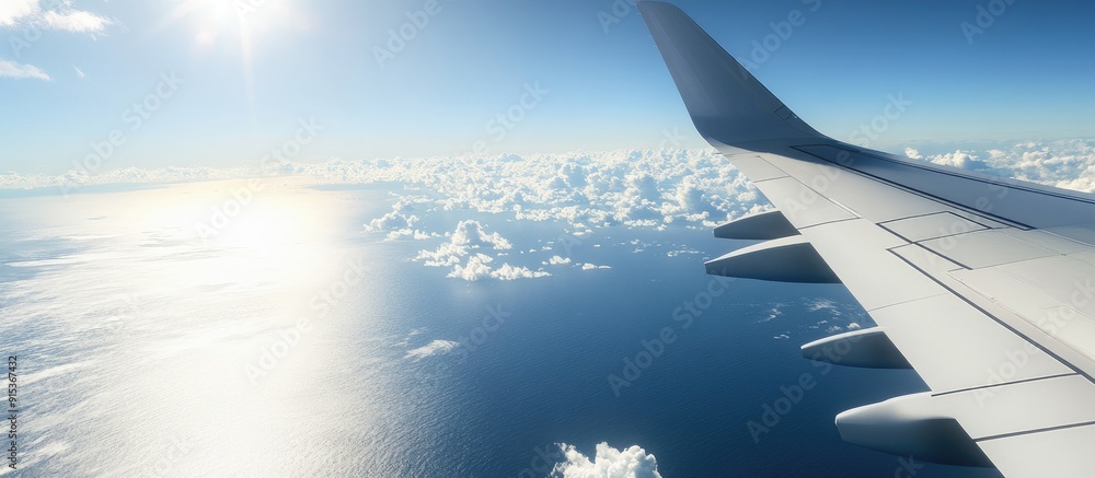 Poster Wing of an airplane above the ocean with a blue sky and clouds. with copy space image. Place for adding text or design