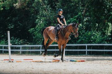Obraz premium Woman riding a horse during an outdoor equestrian training session on a sunny day. Demonstrates skillful horsemanship and passion for horseback riding.