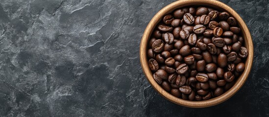 Close up of a wooden bowl filled with roasted coffee beans on a dark slate background Horizontal layout with copy space for text Top view