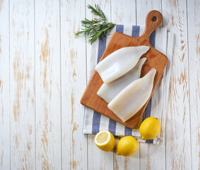 Fresh raw squid fillet with lemons. A large portion of squid is prepared for cooking. Top view.