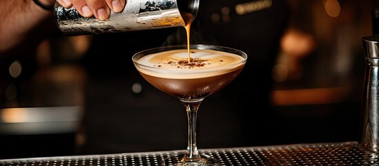 Barman pouring an espresso martini cocktail into a glass at the counter closeup Copyspace available