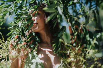 Woman embracing nature, standing among dense green foliage on a sunny day, conveying peace and connection with nature.