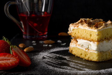 Norwegian cake. With meringue, whipped cream and almonds. Dark background.