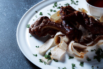 A large piece of spicy grilled meat. Ribs fried to a crisp with spices and herbs. Restaurant serving dishes with sauce and micro-herbs.
