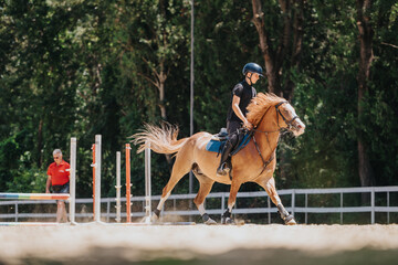 Young horse rider practicing equestrian jumping outdoors, guided by the instructor. The moment...