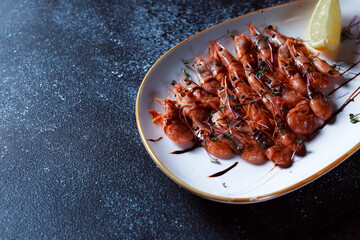 Small red shrimp topped with espaniol sauce. Beautifully served boiled shrimp. Seafood prepared for a restaurant on a dark blue background.