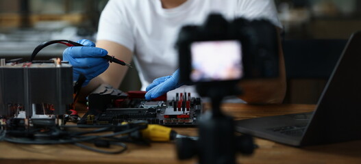 A man makes a video blog on repairing a pc, close-up, blurry. The camera is filming the repair of a digital device