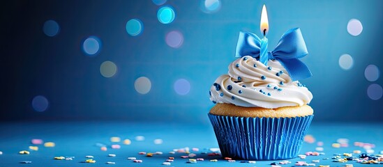 Happy birthday cupcake with a bow candle on a blue background featuring copy space Adorable food inspired happy birthday backdrop idea