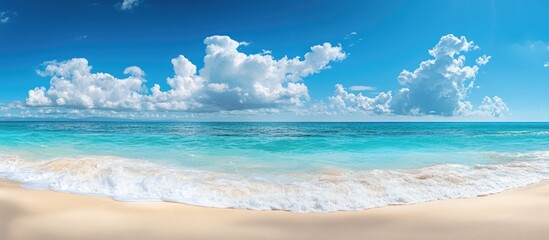 Obraz premium Stunning beach featuring white sand turquoise ocean water and a blue sky on a sunny day Panoramic view backdrop for a summer vacation template with copyspace