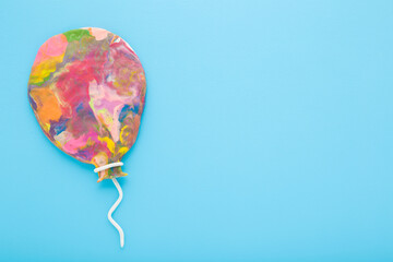 Colorful balloon shape created from modeling clay on light blue table background. Pastel color....