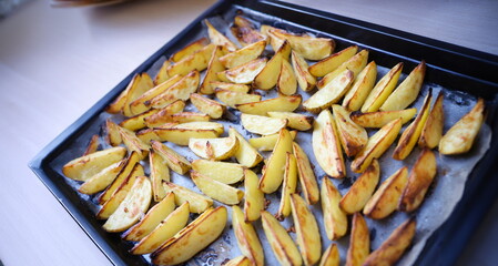 Baked potato wedges on a parchment baking sheet, close-up. Crispy vegetables for lunch, fresh homemade food