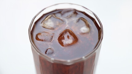 Close-up top view of brown drink with ice. Alcoholic cocktail with cola on a gray background. Cold refreshing soft drink