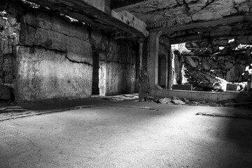 A monochrome photograph captures the haunting beauty of an abandoned building’s interior with a...