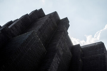 The image shows the modern Gdańsk theater building with its distinctive architectural design against a backdrop of a cloudy sky.