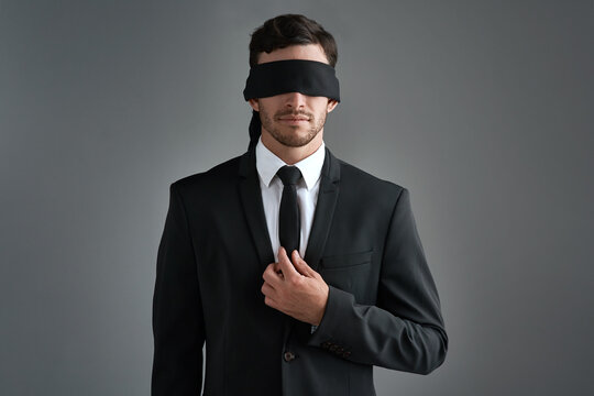 Dark, professional and man with blindfold in studio for challenge, control and censorship of career slavery. Person, blinded and lost for struggle, inequality and opportunity doubt on gray background