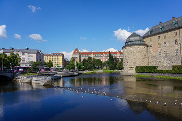 View of buildings by river against blue sky in Örebro