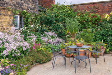 Charming cottage garden with terracotta planters, table and chairs.