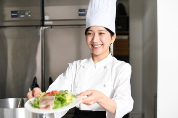 料理を提供する若いアジア人の女性調理師