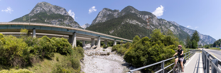 Obraz premium woman with e-bike on the alpe adria cycle route ( Pontebanna ) through the Val Canale in Italy