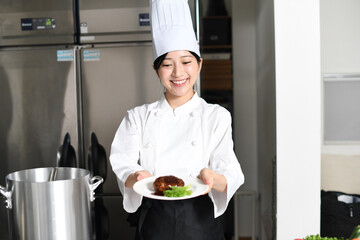 肉料理を提供する若いアジア人の女性調理師