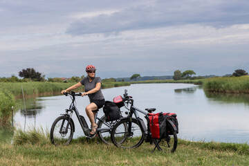 Obraz premium Woman cycling through regional nature reserve of the mouth of the Isonzo,Friuli Venezia Giulia, Italy