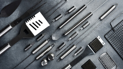 Fototapeta premium Steel utensils for grilling. On a gray concrete background. Top view.