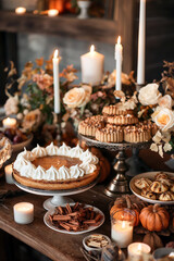 A Thanksgiving dessert table featuring a pumpkin cheesecake with a gingerbread crust, surrounded by other seasonal treats, candles, and autumnal decorations.