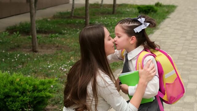 back to school, a schoolgirl runs to her mother hugging her, a parent picks up a child, a girl from school, a student with a backpack meets with her mother