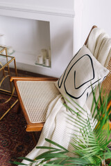 Comfy and rattan chair with decorative pillow and plaid