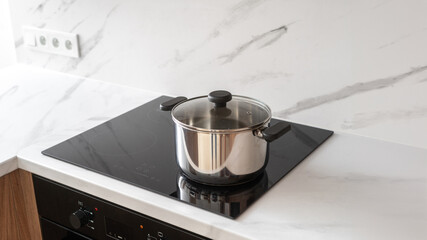 Stainless steel pot on induction cooktop in modern kitchen