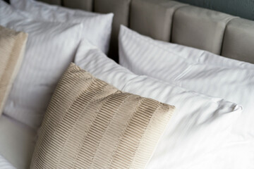 Close up of bed with decorative cushions and white pillows