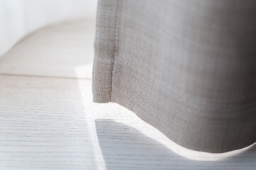 A fragment of a linen curtain close-up. Shadow from the curtains on the floor