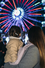 Mother and Daughter Watching Ferris Wheel at Christmas in Alcala de Henares. Mother and daughter, backs turned, watching the Christmas Ferris wheel at night in Alcala de Henares.
