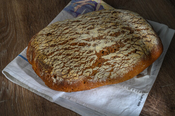 Traditional leavened sourdough bread with rought skin on a rustic wooden table. Healthy food photography