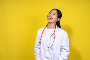 A woman in a white lab coat is smiling and holding a stethoscope