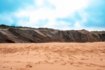 A tranquil beach scene, a rocky outcrop, and the soft sand, capturing the serene beauty of coastal nature.