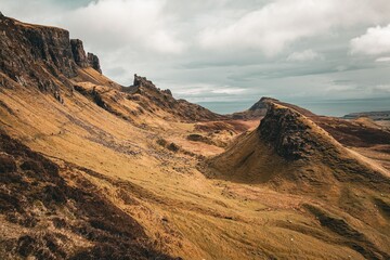 Naklejka premium landslip on the Isle of Skye, Scotland, with rugged cliffs and rolling hills under a cloudy sky