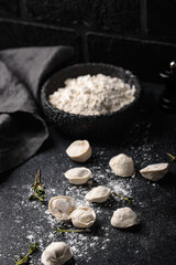 Raw dumplings or ravioli on black background