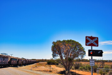 Railway crossing and railway with a freight train in the Western Australian outback