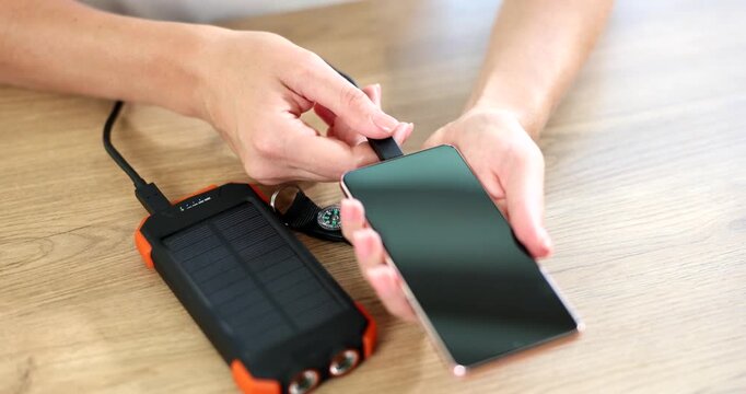 Hands connecting mobile phone to solar power bank closeup 4k movie slow motion. Energy saving devices concept